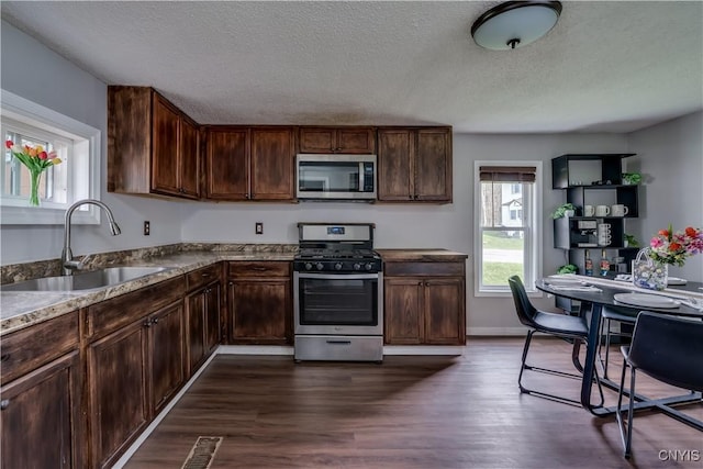 kitchen with visible vents, a textured ceiling, a sink, dark wood finished floors, and stainless steel appliances