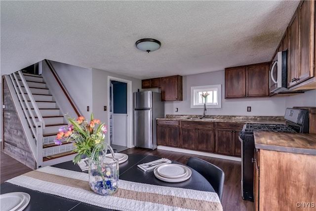kitchen with a sink, appliances with stainless steel finishes, dark wood finished floors, and a textured ceiling