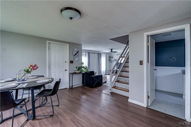 dining area with ceiling fan, a textured ceiling, wood finished floors, visible vents, and stairway