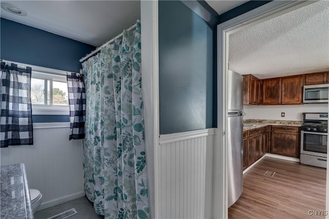 full bathroom featuring a shower with curtain, a textured ceiling, visible vents, vanity, and toilet