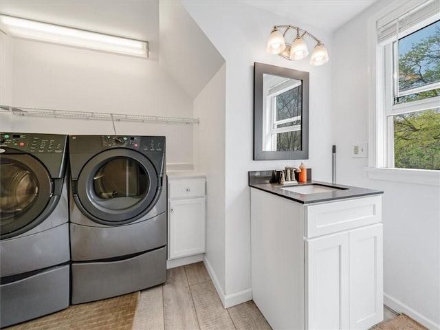 laundry room with baseboards, washing machine and dryer, a sink, and a healthy amount of sunlight