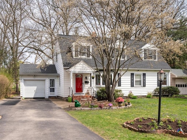 new england style home featuring an attached garage, a shingled roof, a front lawn, and aphalt driveway