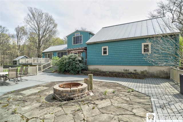rear view of house featuring a patio, metal roof, an outdoor fire pit, and a deck