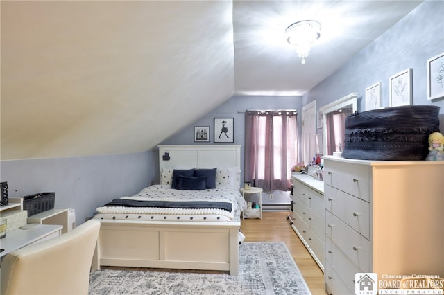 bedroom with vaulted ceiling, baseboard heating, and light wood-style floors