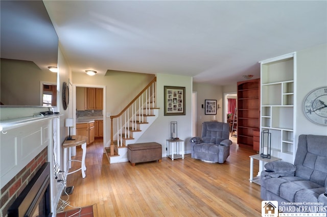 living area with stairway, a fireplace, and light wood-type flooring