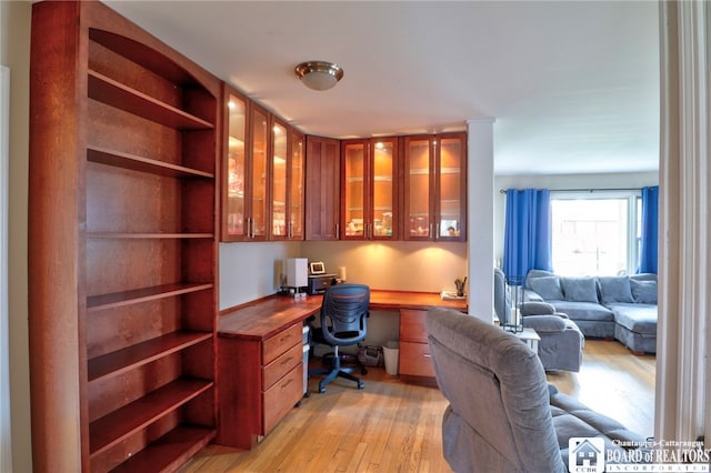 office space with built in desk and light wood-type flooring