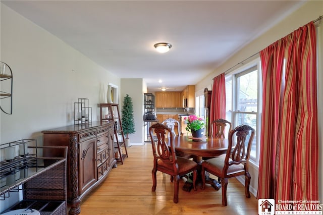 dining space with baseboards and light wood-type flooring