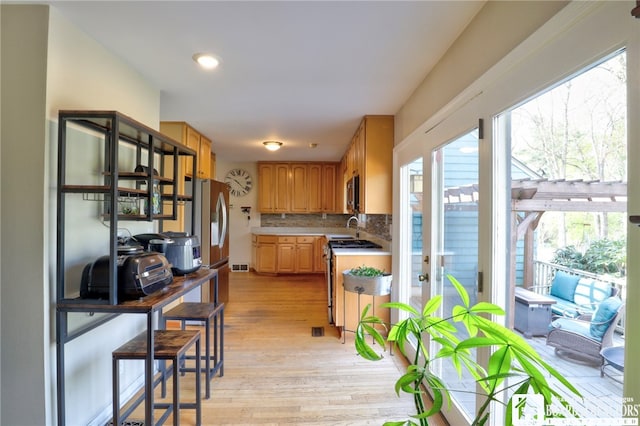 kitchen with visible vents, decorative backsplash, light countertops, light wood-style flooring, and appliances with stainless steel finishes