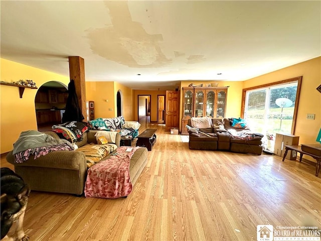 living area with arched walkways and light wood-type flooring