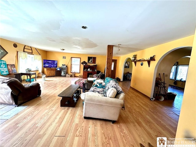 living area featuring arched walkways and wood finished floors