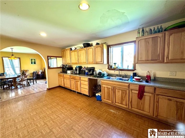 kitchen featuring recessed lighting, arched walkways, a sink, and hanging light fixtures