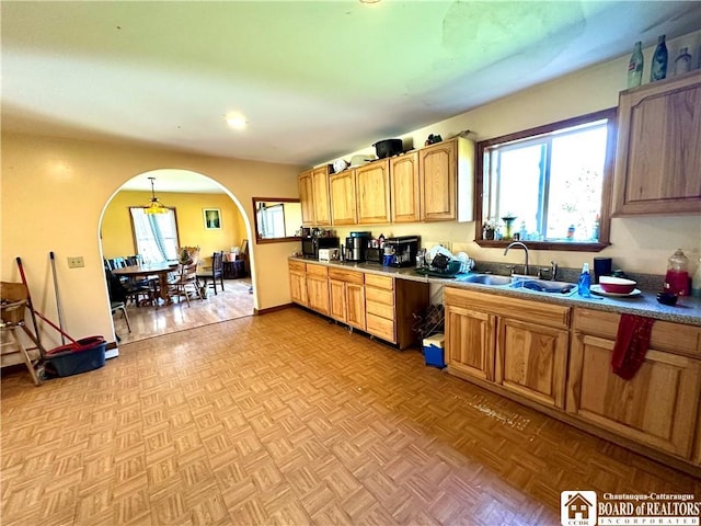 kitchen featuring a sink, arched walkways, and pendant lighting