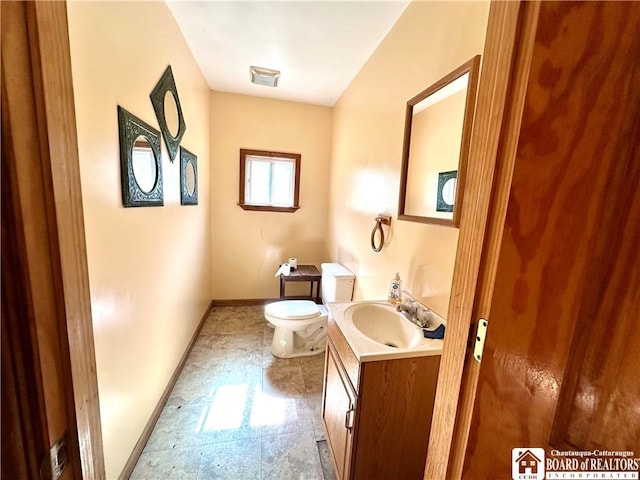 half bath with baseboards, vanity, and toilet
