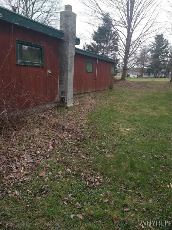 view of side of home featuring a yard and a chimney