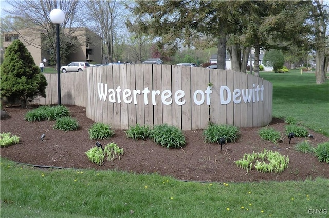 community / neighborhood sign featuring a lawn and fence