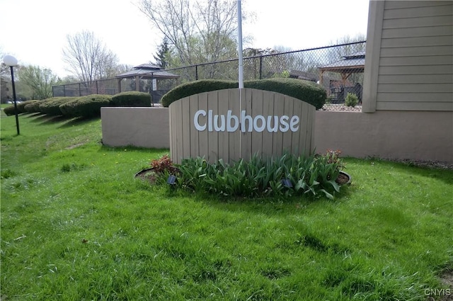 community / neighborhood sign featuring a lawn and fence