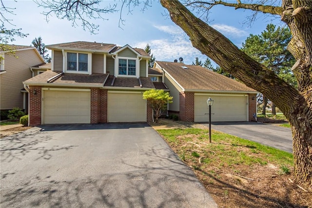 view of front of property with brick siding, an attached garage, and aphalt driveway