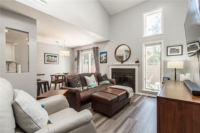 living room with a glass covered fireplace, baseboards, dark wood-style floors, and a towering ceiling
