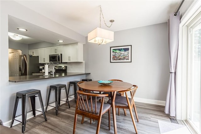 dining area featuring baseboards, a notable chandelier, and wood finished floors