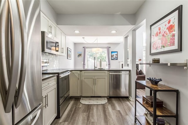 kitchen with dark countertops, appliances with stainless steel finishes, a sink, a peninsula, and dark wood-style floors
