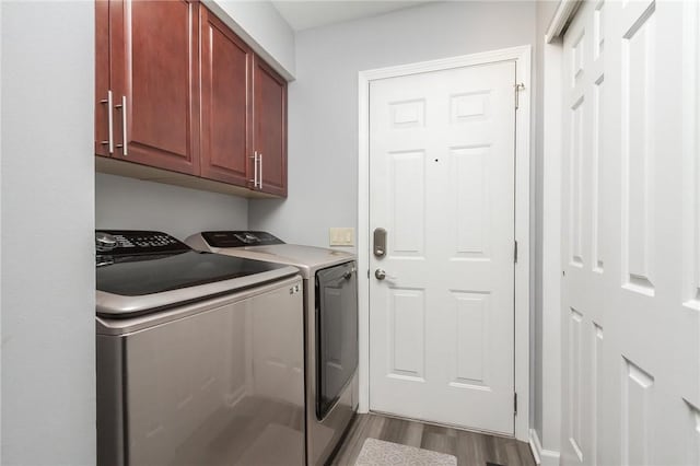clothes washing area with washer and clothes dryer, cabinet space, and wood finished floors