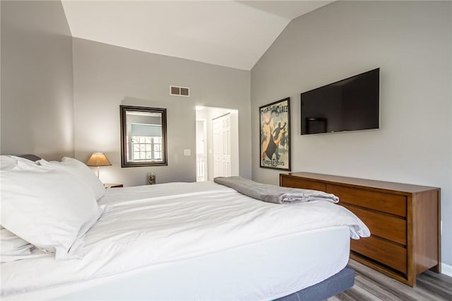 bedroom with visible vents, wood finished floors, and vaulted ceiling