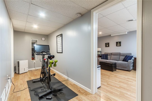 workout room with baseboards, visible vents, a paneled ceiling, and wood finished floors