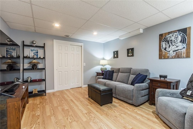 living room featuring a drop ceiling and light wood-style flooring