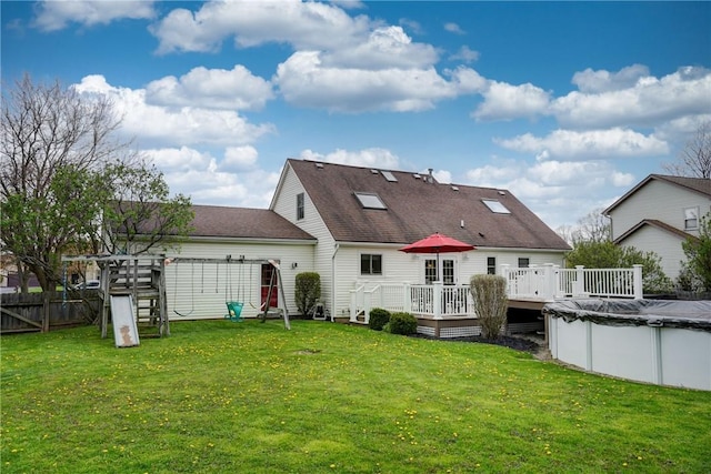 back of property with roof with shingles, a lawn, a deck, fence, and a covered pool