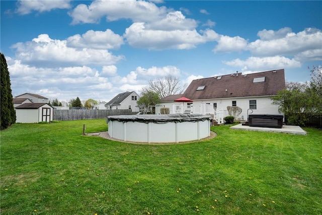 view of yard featuring a storage unit, a hot tub, a fenced backyard, a fenced in pool, and an outdoor structure