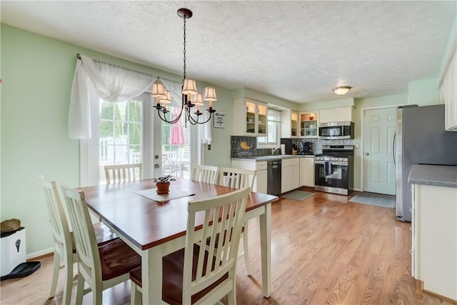 dining area with a textured ceiling, an inviting chandelier, and light wood-style floors