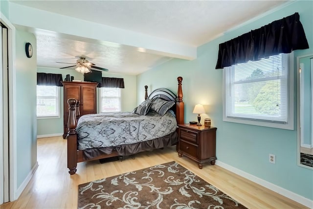 bedroom featuring light wood-style floors, baseboards, ceiling fan, and beamed ceiling
