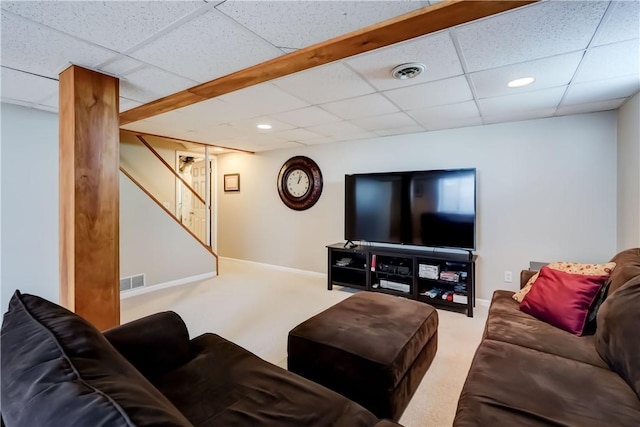 carpeted living area featuring baseboards, a drop ceiling, stairs, and visible vents