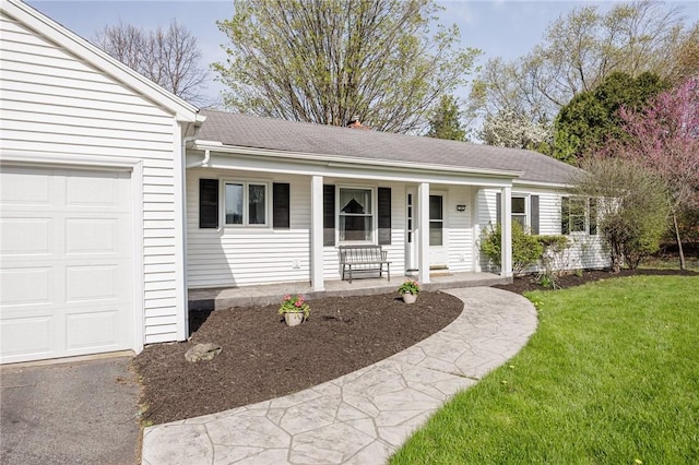 ranch-style house with a porch, roof with shingles, an attached garage, and a front yard