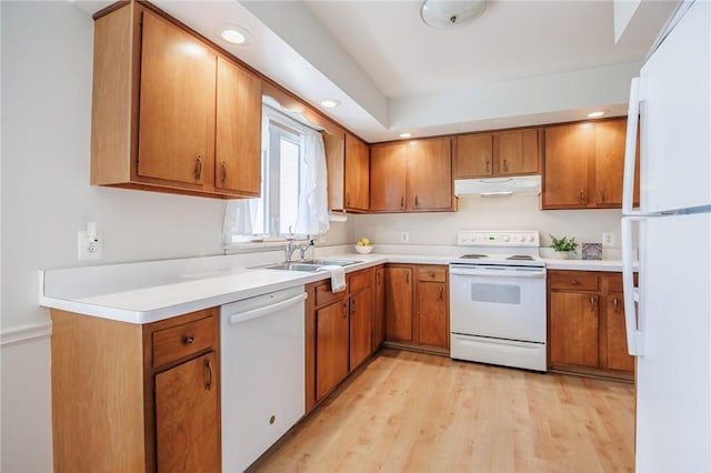 kitchen with brown cabinets, a sink, white appliances, light countertops, and under cabinet range hood