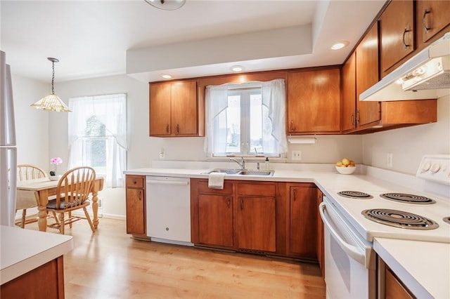 kitchen featuring a sink, brown cabinets, under cabinet range hood, and white appliances