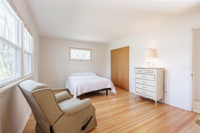 bedroom with a closet, baseboards, and light wood-style floors