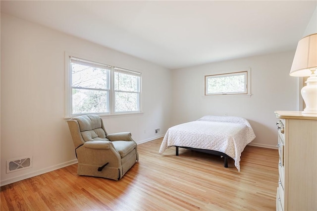 bedroom with baseboards, visible vents, and light wood finished floors