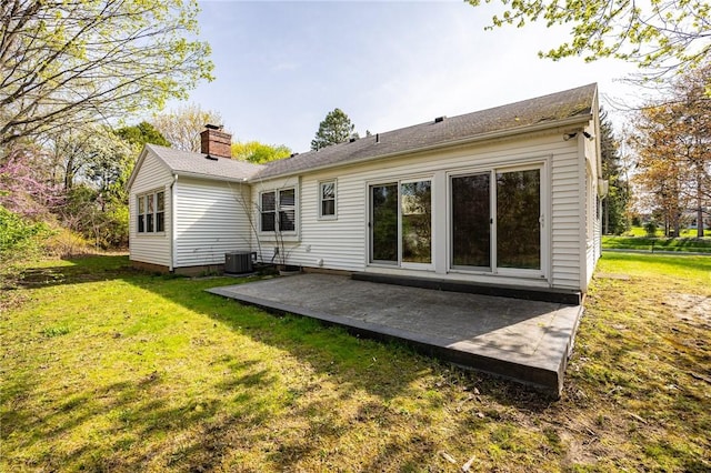 rear view of house featuring a yard, central AC, a chimney, and a patio area