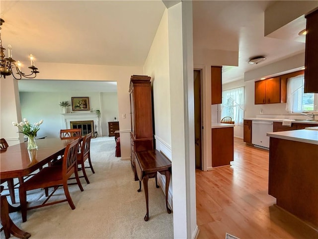 dining area with a glass covered fireplace, light wood finished floors, and a chandelier