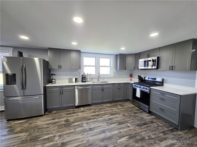 kitchen with gray cabinetry, appliances with stainless steel finishes, dark wood-style floors, and a sink