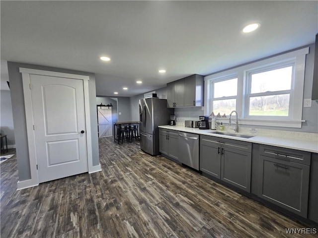 kitchen featuring gray cabinetry, stainless steel appliances, dark wood-style flooring, and a sink
