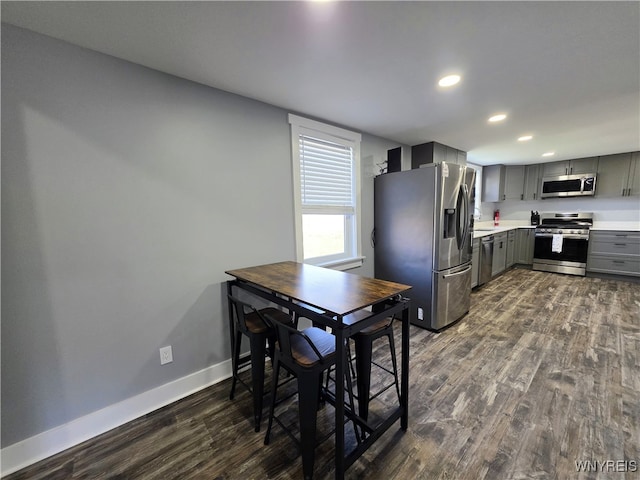 kitchen with appliances with stainless steel finishes, light countertops, dark wood finished floors, gray cabinets, and recessed lighting