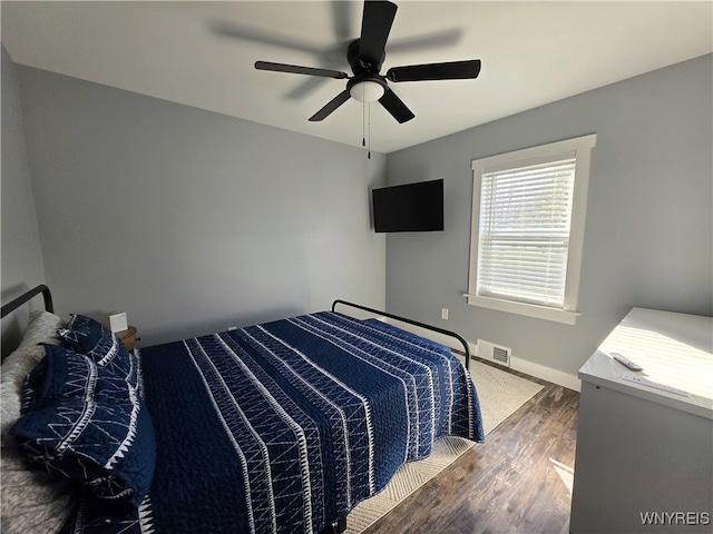 bedroom featuring a ceiling fan, baseboards, visible vents, and wood finished floors
