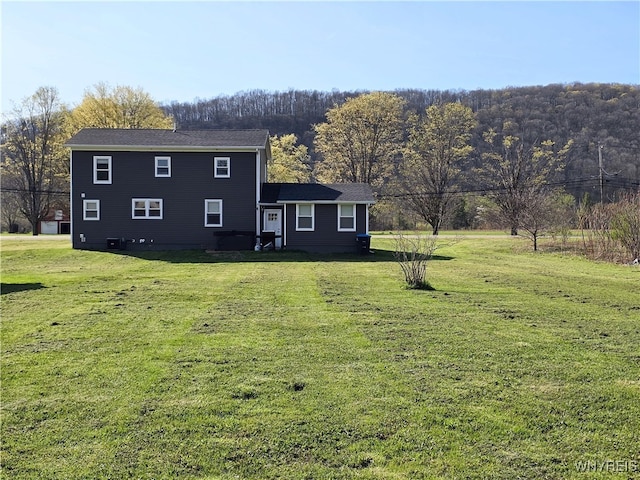 view of front of home with a front yard and a forest view