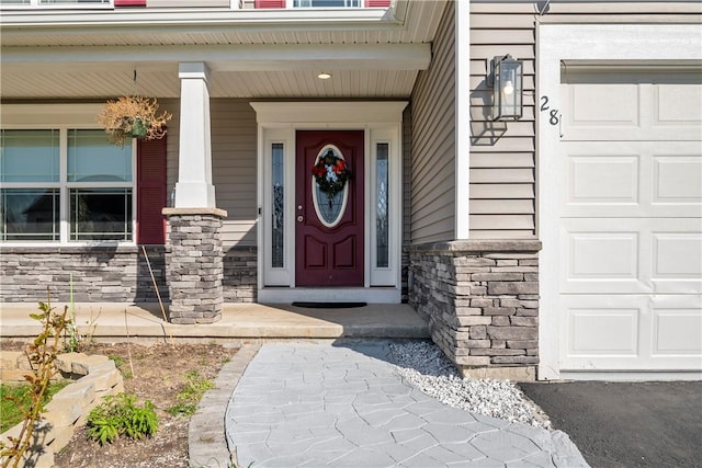 doorway to property with a porch, an attached garage, and stone siding