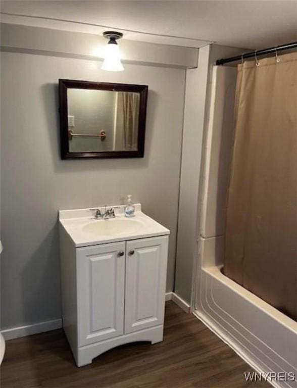 bathroom featuring baseboards, wood finished floors, shower / tub combo, and vanity
