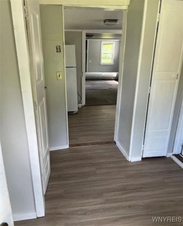 corridor featuring baseboards and wood finished floors