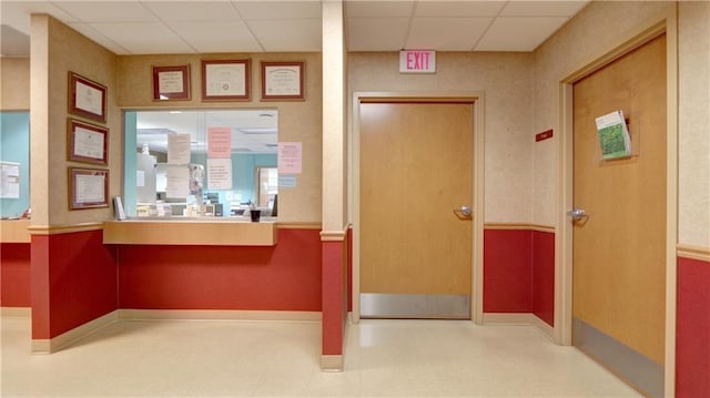 interior space with baseboards, a drop ceiling, and tile patterned floors