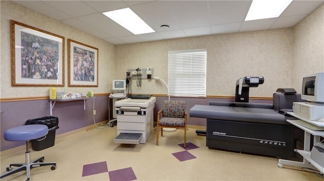misc room with a drop ceiling and wallpapered walls